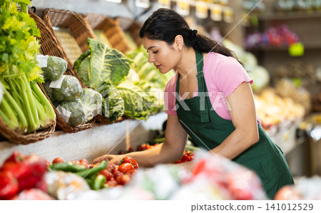 Woman worker seller in grocery vegetable shop and tomato Woman worker seller in grocery vegetable shop and tomato 141012529