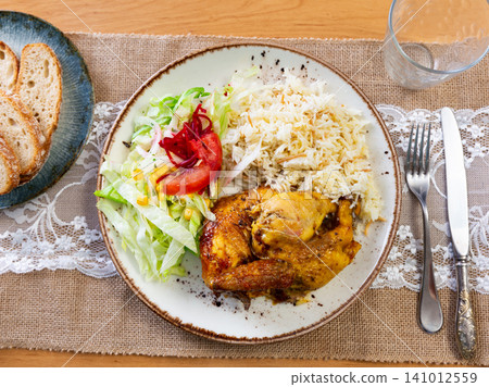 Tender meat of roasted chicken is garnished with boiled rice, vegetable salad. Tender meat of roasted chicken is garnished with boiled rice, vegetable salad. 141012559