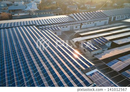 Aerial view of solar power plant with blue photovoltaic panels mounted on industrial building roof for producing green ecological electricity. Production of sustainable energy concept Aerial view of solar power plant with blue photovoltaic panels mounted on industrial building roof for producing green ecological electricity. Production of sustainable energy concept 141012567