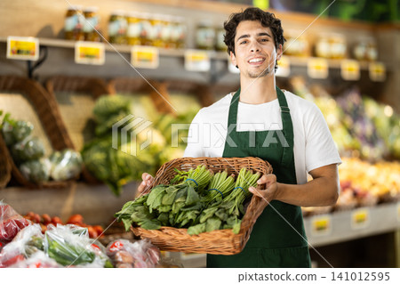 Man worker seller in grocery vegetable shop assort spinach Man worker seller in grocery vegetable shop assort spinach 141012595