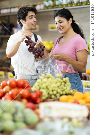 Couple choosing grapes at grocery store 141012630