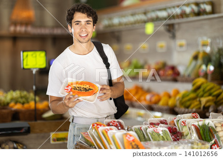 Male shopper selects ripe papaya grocery supermarket Male shopper selects ripe papaya grocery supermarket 141012656