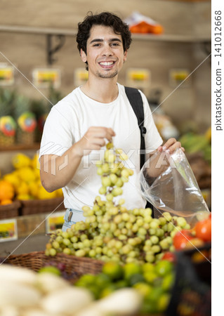 Man shopping, examine vegetable in store and buy elect grape. Man shopping, examine vegetable in store and buy elect grape. 141012668