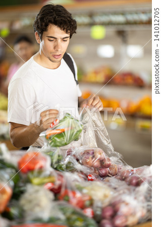 Man choose pick up vegetables in in plastic bags Man choose pick up vegetables in in plastic bags 141012705