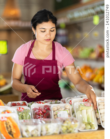 Female seller working with packaged vegetables and fruits at grocery store Female seller working with packaged vegetables and fruits at grocery store 141012749