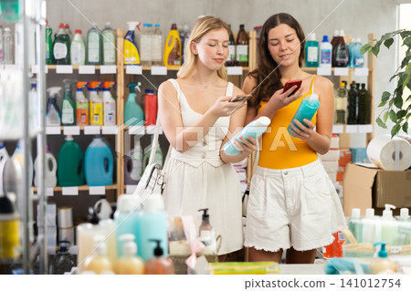 Women friends scanning qr code for shampoo or shower gel Women friends scanning qr code for shampoo or shower gel 141012754