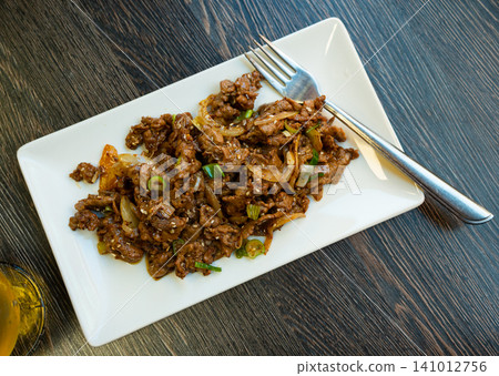 Portion of Chinese food is pieces of fried beef tenderloin with soy-cumin sauce Portion of Chinese food is pieces of fried beef tenderloin with soy-cumin sauce 141012756