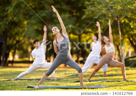 Woman performing Bound Reverse Warrior Pose during group yoga Woman performing Bound Reverse Warrior Pose during group yoga 141012766