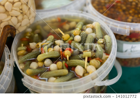 Marinated green olives, onions, cucumbers, peppers in a plastic container at market Marinated green olives, onions, cucumbers, peppers in a plastic container at market 141012772