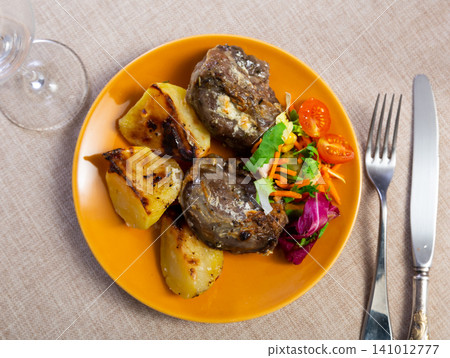 Pork cheek served with potatoes and vegetable salad Pork cheek served with potatoes and vegetable salad 141012777