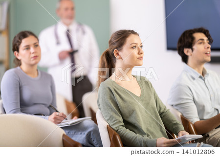 Female student listening to a lecture against the background of a doctor Female student listening to a lecture against the background of a doctor 141012806