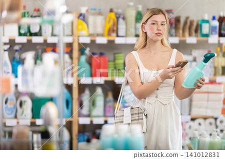 woman in summer clothes scans a qr code on a package of surface cleaning spray woman in summer clothes scans a qr code on a package of surface cleaning spray 141012831