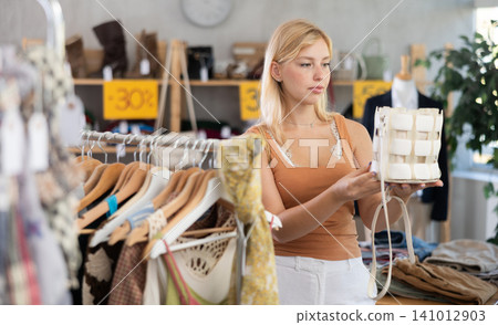 Fashionista girl near showcase examine goods, buying handbag Fashionista girl near showcase examine goods, buying handbag 141012903