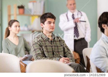 Young guy watching presentation with a doctor standing in background Young guy watching presentation with a doctor standing in background 141012909