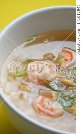 rice soup with shrimp in white bowl on yellow background rice soup with shrimp in white bowl on yellow background 141012945