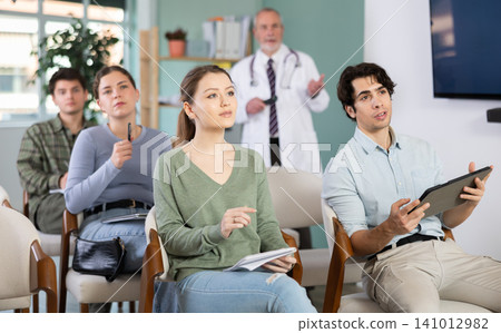 Young students watching presentation with a doctor standing in background Young students watching presentation with a doctor standing in background 141012982