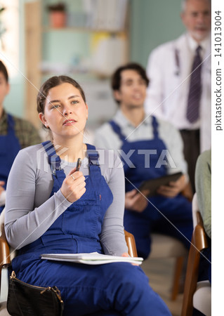 Young female student worker listening to lecture with medical professor in background Young female student worker listening to lecture with medical professor in background 141013004