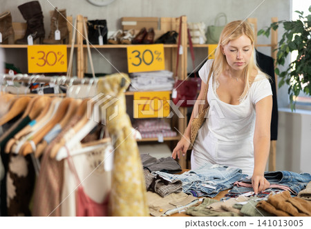 Fashionista girl near showcase examine goods, buying shorts or trousers 141013005