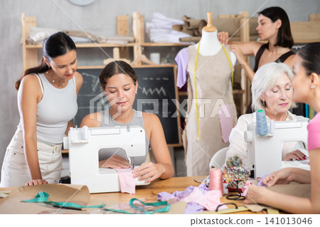 Group of women enjoying teamwork during hands-on dressmaking class Group of women enjoying teamwork during hands-on dressmaking class 141013046