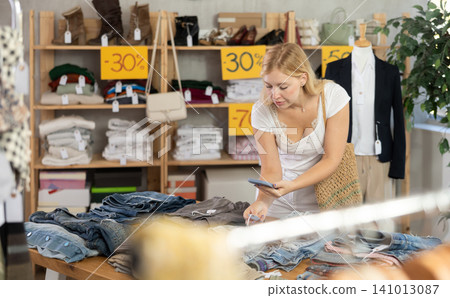 Young female customer scans QR code on trousers or shorts label Young female customer scans QR code on trousers or shorts label 141013087