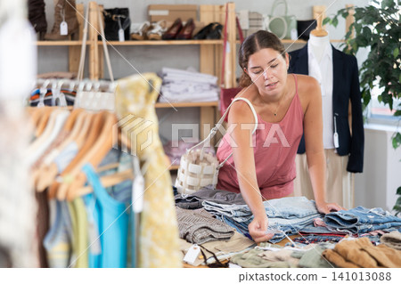 Fashionista girl near showcase examine goods, buying shorts or trousers 141013088