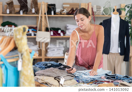 Young woman scanning qr code of trousers in clothing store Young woman scanning qr code of trousers in clothing store 141013092