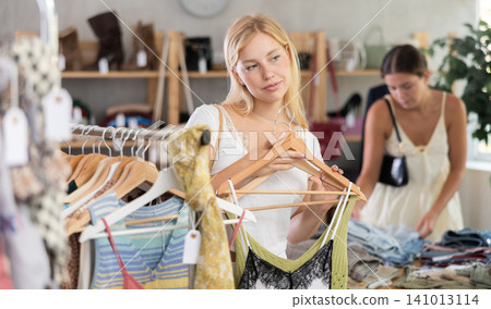 Young woman with her friend choosing top in store Young woman with her friend choosing top in store 141013114