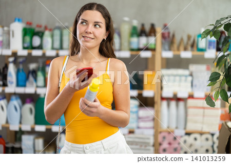 Girl buyer scans qr code on mosquito repellent label Girl buyer scans qr code on mosquito repellent label 141013259