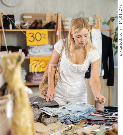 Woman chooses pants at discounts 141013278