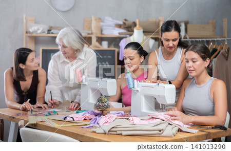 Group of busy women sewing and drawing with teacher at dressmaking courses Group of busy women sewing and drawing with teacher at dressmaking courses 141013290