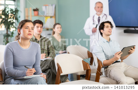 Young female student listening to lecture with medical professor in background 141013295