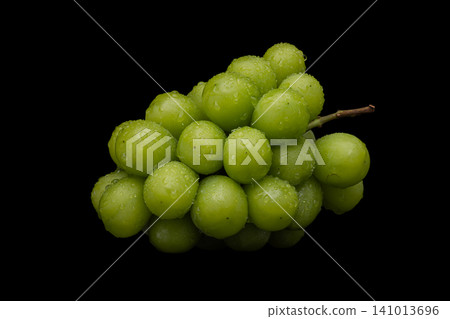 A photograph of wet Shine Muscat grapes against a black background. A photograph of wet Shine Muscat grapes against a black background. 141013696