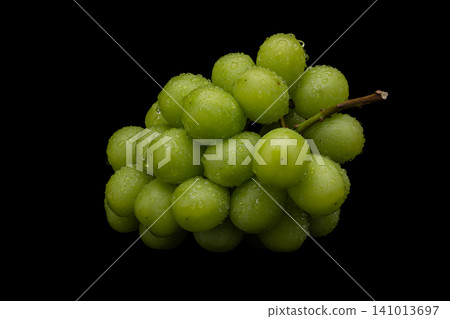 A photograph of wet Shine Muscat grapes against a black background. A photograph of wet Shine Muscat grapes against a black background. 141013697
