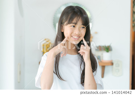 Elementary school girl looking in the mirror Elementary school girl looking in the mirror 141014042