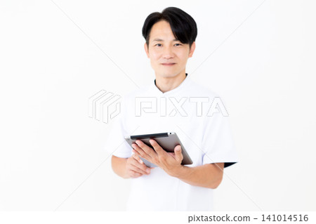 A middle-aged male acupuncturist/osteopath in a white coat holding a tablet. 141014516
