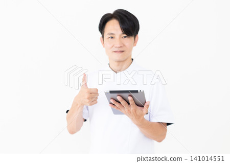身穿白大褂的中年男性針灸師/整骨師,手持藥片,豎起大拇指。 身穿白大褂的中年男性針灸師/整骨師,手持藥片,豎起大拇指。 141014551