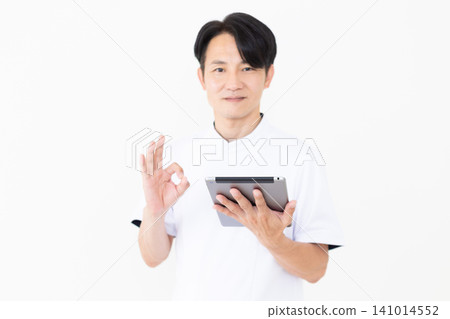 一位身穿白大褂的中年男性針灸師/整骨師,手持平板電腦,擺出一個圓圈姿勢。 一位身穿白大褂的中年男性針灸師/整骨師,手持平板電腦,擺出一個圓圈姿勢。 141014552