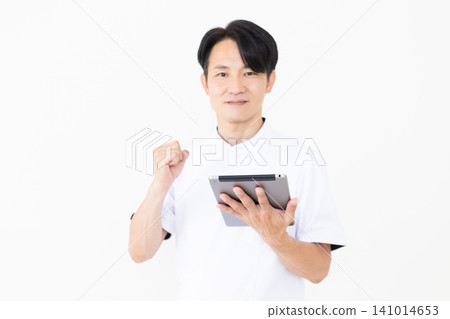 一位身穿白大褂的中年男性針灸師/整骨師手持平板電腦,做出勝利的手勢。 一位身穿白大褂的中年男性針灸師/整骨師手持平板電腦,做出勝利的手勢。 141014653