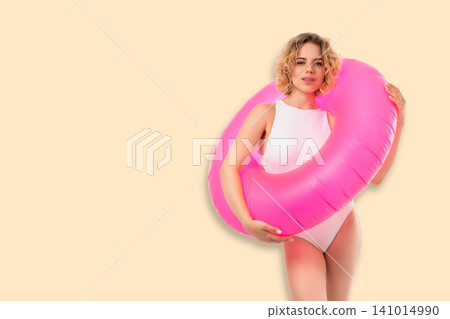 Woman showcases trendy swimsuit while holding bright float. Summer vibes and beauty concept Woman showcases trendy swimsuit while holding bright float. Summer vibes and beauty concept 141014990