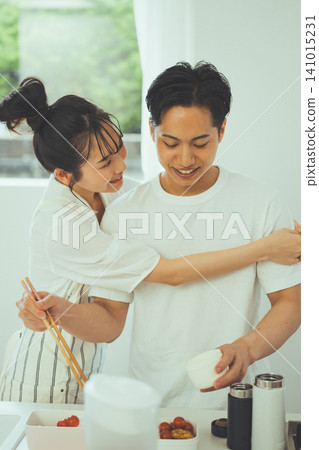 A kitchen scene featuring a man with a big smile on his face as a woman hugs him from behind. A kitchen scene featuring a man with a big smile on his face as a woman hugs him from behind. 141015231