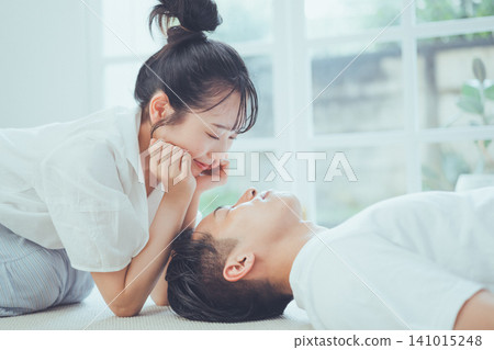 一個浪漫的場景:一位女子麵帶微笑,凝視著正在小憩的男子熟睡的臉龐。 一個浪漫的場景:一位女子麵帶微笑,凝視著正在小憩的男子熟睡的臉龐。 141015248