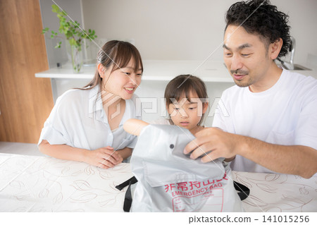 一家三口一邊檢查應急包裡的物品,一邊討論災難準備狀況,以此說明他們應對地震和災害的方法。 一家三口一邊檢查應急包裡的物品,一邊討論災難準備狀況,以此說明他們應對地震和災害的方法。 141015256