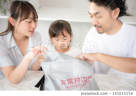 一家三口一邊檢查應急包裡的物品,一邊討論災難準備狀況,以此說明他們應對地震和災害的方法。 一家三口一邊檢查應急包裡的物品,一邊討論災難準備狀況,以此說明他們應對地震和災害的方法。 141015258