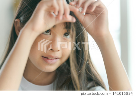 一個女孩在玩弄她的頭髮 一個女孩在玩弄她的頭髮 141015854