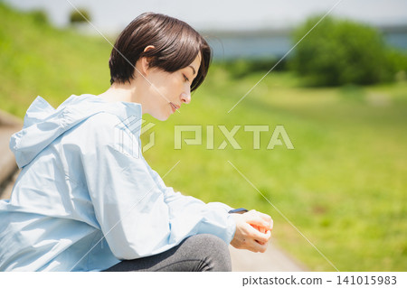年輕女子正在查看她的運動手錶。運動圖片。 年輕女子正在查看她的運動手錶。運動圖片。 141015983