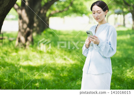 操作智慧型手機的年輕女性 — 生活方式形象 操作智慧型手機的年輕女性 — 生活方式形象 141016015