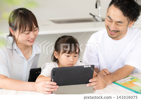 An image of a family of three (parents and two children) using a tablet for home learning, and an illustration of digital education. 141016075