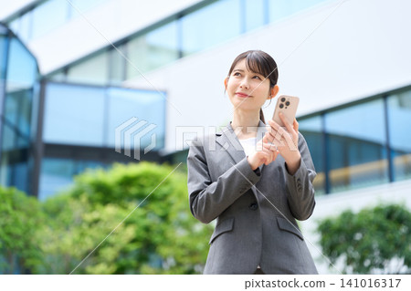 A businesswoman using her smartphone outdoors. 141016317