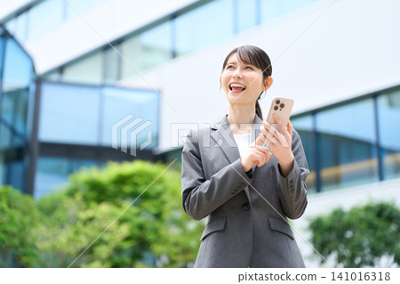 A businesswoman using her smartphone outdoors. 141016318