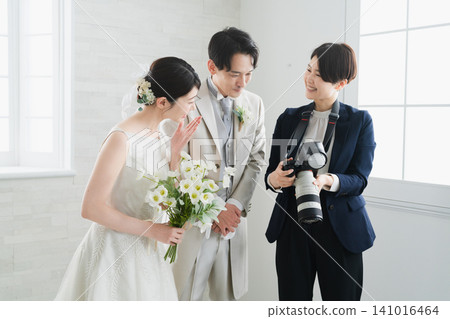 新娘和新郎檢查攝影師拍攝的婚禮照片 新娘和新郎檢查攝影師拍攝的婚禮照片 141016464